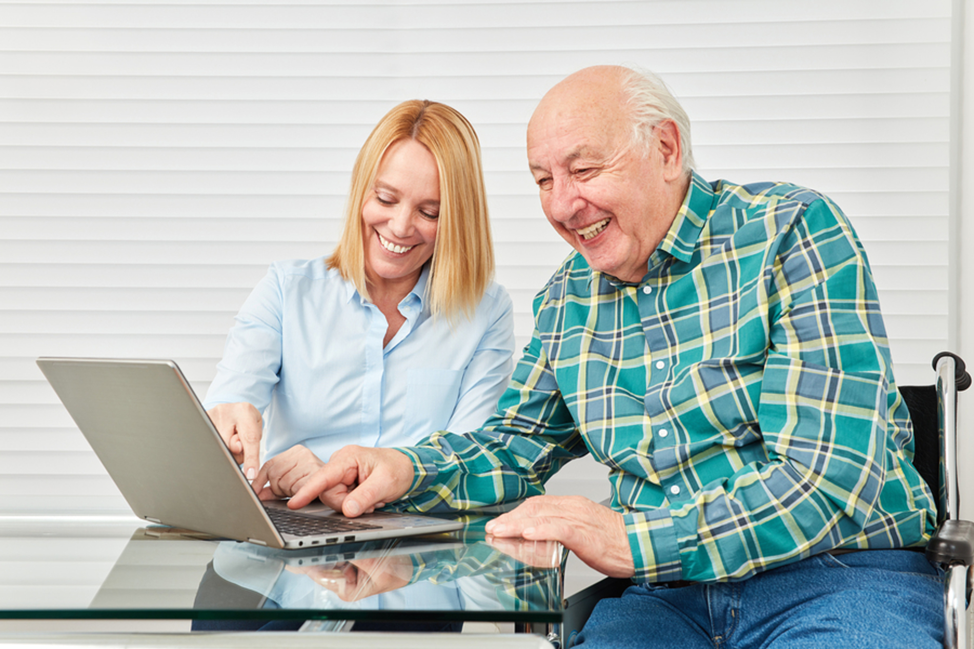 Father and daughter sitting at a table working on a laptop.